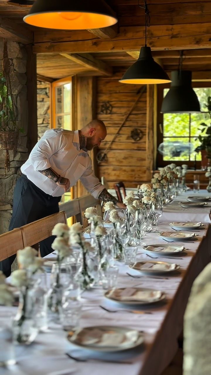 Číšník prostírá dlouhou svatební tabuli v restauraci