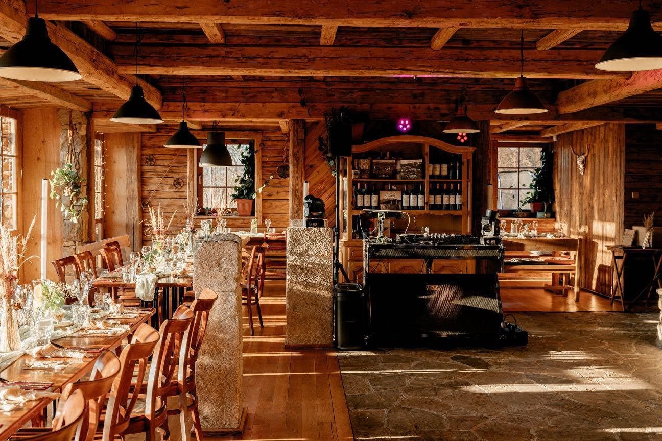 Restaurace Berry večer — trámový strop, lampy nad stoly a bar v pozadí