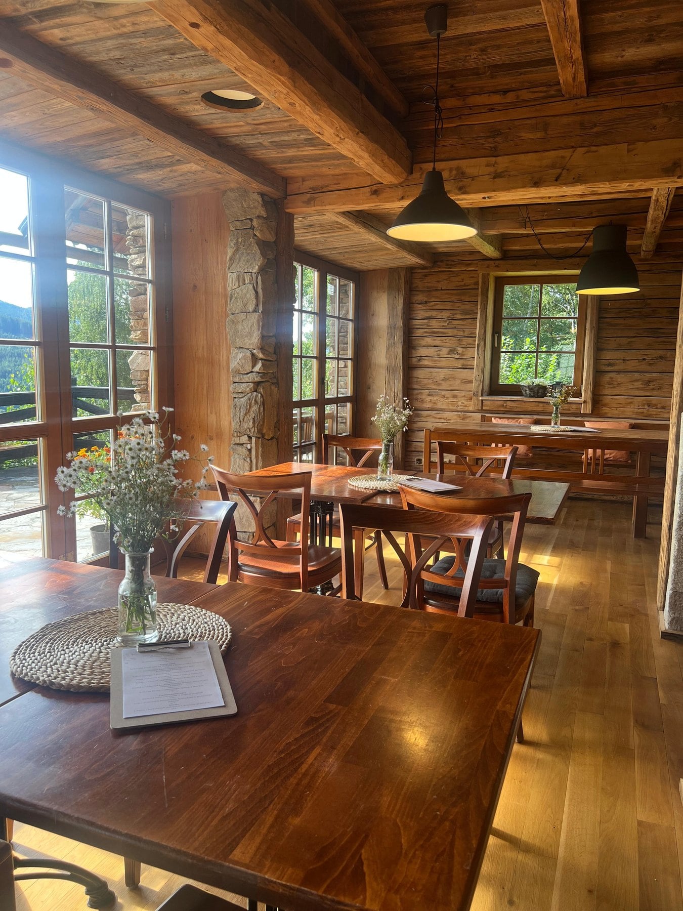 Holzinterieur des Restaurants mit Balkendecke und Fenstern zu den Bergen
